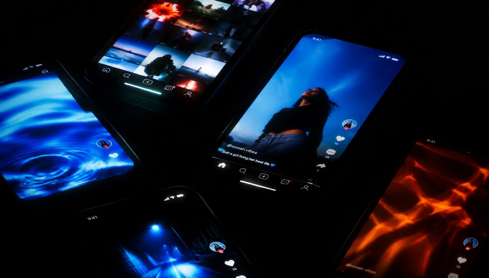Smartphones glowing with social video feeds in a dark room